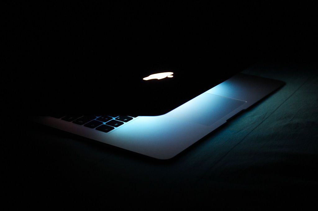 MacBook Air semi aberto com luz iluminando e fundo escuro